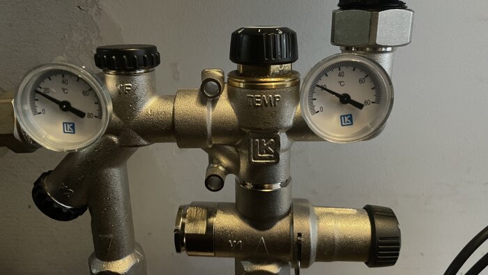 Två termometrar på en värmesysteminstallation visar temperaturer på 18 och 20 grader Celsius.