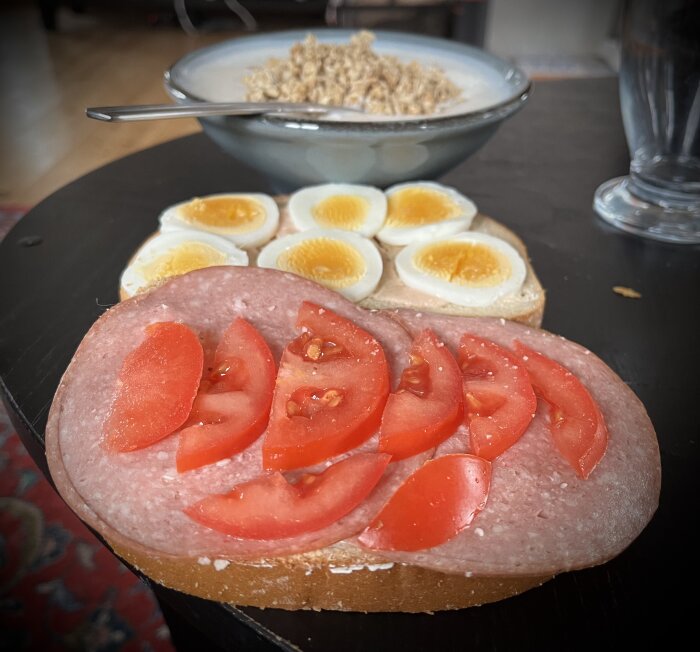 Macka med salami och tomat, halva kokta ägg, skål med flingor i bakgrunden.