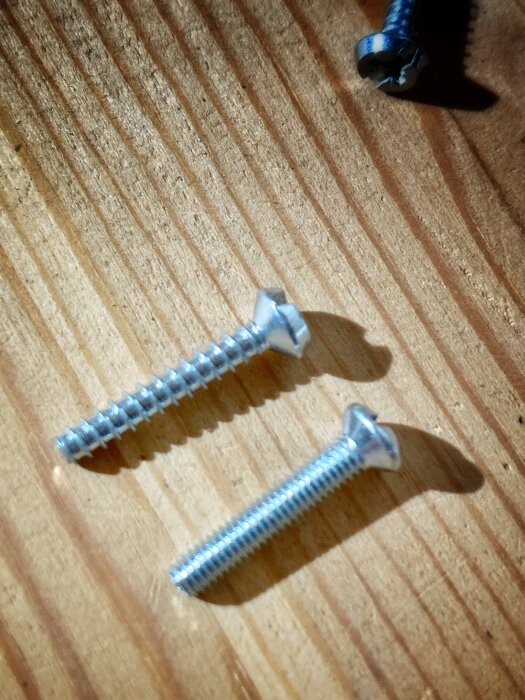 Tre skruvar med olika gängning på träyta relaterade till elinstallation.