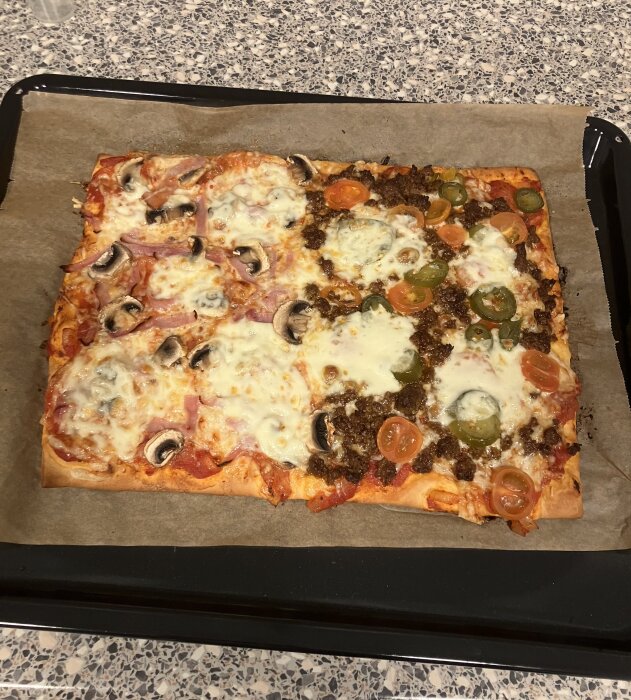 Hemlagad pizza med hälften tacofärs och jalapeños, hälften rökt skinka, svamp, småtomater och mozzarella.