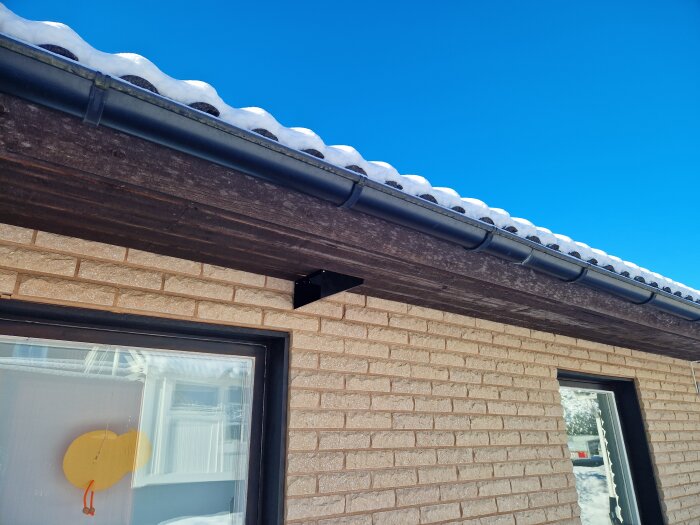 Takfot med hängränna på ett hus, täckt av snö, visar spirot draget längs takfoten.