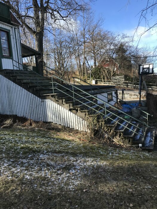 Ihålig betongtrappa utomhus, bredvid ett hus, med räcke, täckt med snöfläckar.