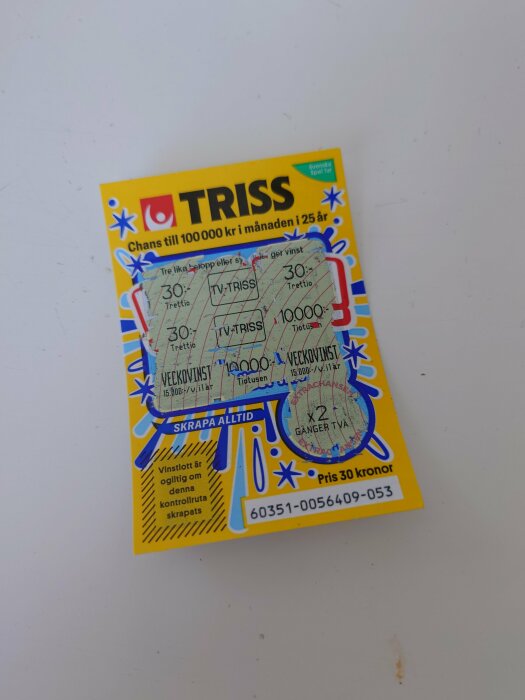 Skraplott från Triss med delvis skrapade rutor på en vit yta.