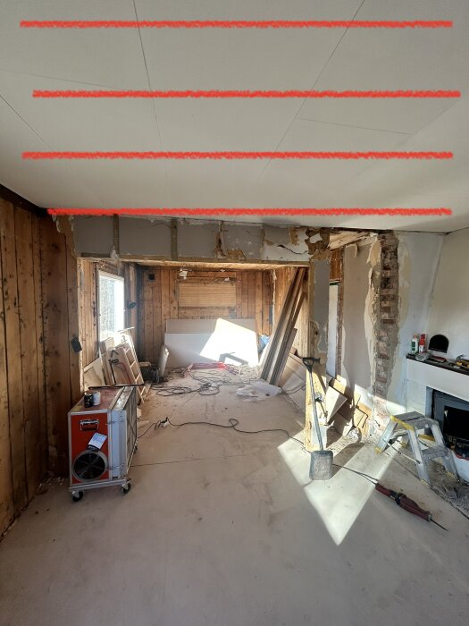 Renoveringsarbete pågår i rum med borttaget tegel på vägg, avstämda takbjälkar och byggmaterial utspritt.