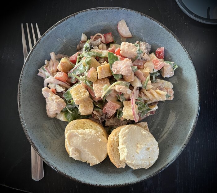 Kycklingsallad med diverse grönsaker och bbq-dressing, serverad med crostini toppad med hummus.