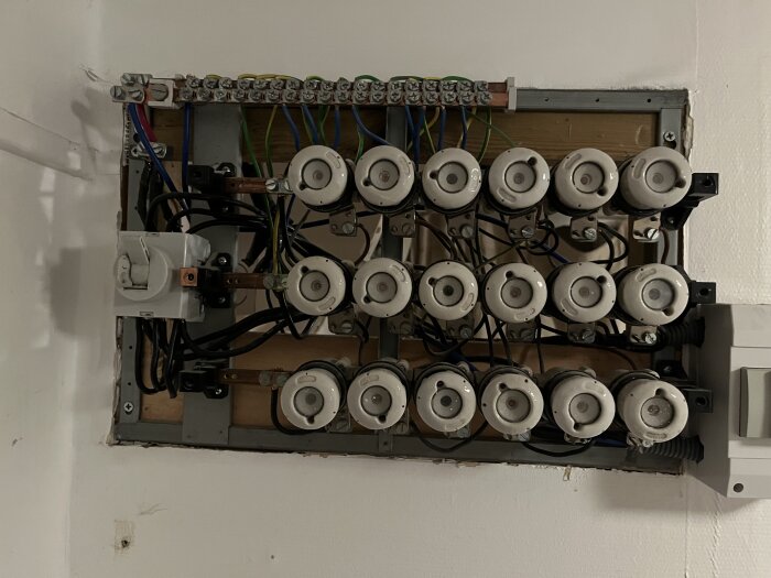 Gammal säkringstavla med säkringshållare och anslutna kablar i behov av modernisering.