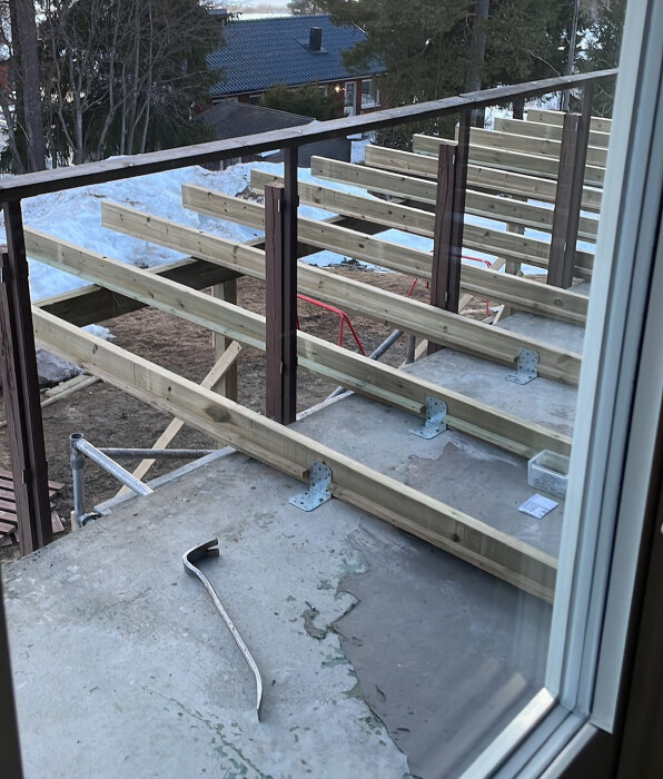 Uppbyggnad av balkongkonstruktion med nyinstallerade träribbor och metallbeslag på en betonggrund.