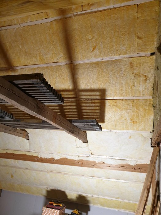 Renoverad kattvind med ny limträbalk inbyggd i isolerat tak, synlig stomme och reglar.