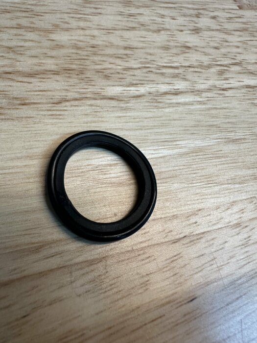 Svart o-ring ligger på en träyta, tillhör en packbox som användaren försökt fiska ut.