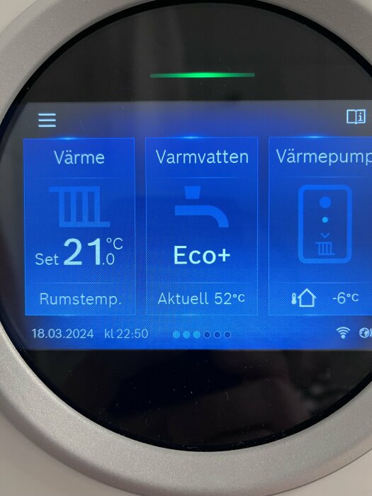 En termostatdisplay som visar värmeinställningar och temperaturer för värme, varmvatten och värmepump.