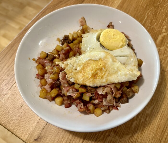 Tallrik med traditionell pyttipanna, toppad med stekt ägg och rödbetsskiva.