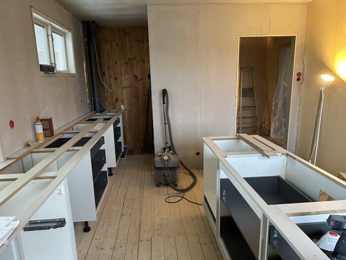 Renoveringsprojekt med utplacerade köksskåp i ett rum under förberedelse för spackling och målning.