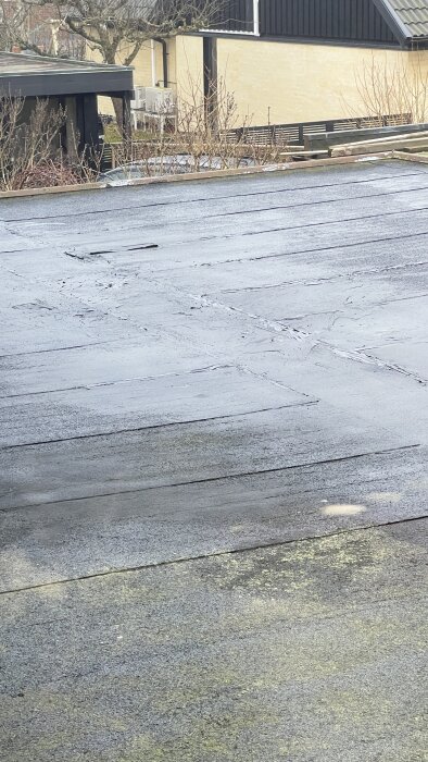 Slitet garagetak med gammalt takpapper som uppvisar sprickor och slitage.