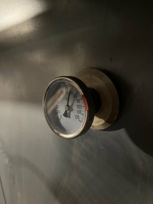 Analog vattentemperaturmätare på en ackumulatortank i en mörk miljö.