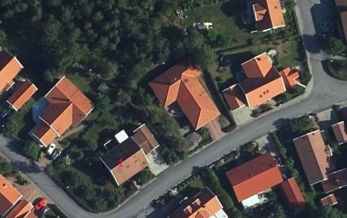 Flygbild över ett bostadsområde som visar två fastigheter med numrerade byggnader och potentiell gränsdispyt.