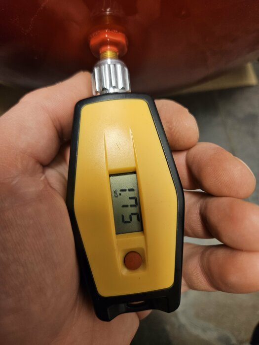 Digital manometer i förgrunden visar 1,5 bar, kopplad till ett rörligt kärl i bakgrunden.