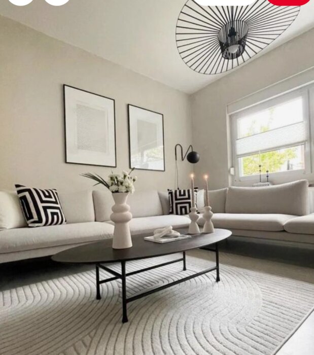 Ett vardagsrum i ljusbeige med vita soffor, svart bord och minimalistisk dekor.