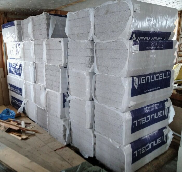 Staplar av vita isoleringsblock av EPS-material inplastade på en byggarbetsplats.