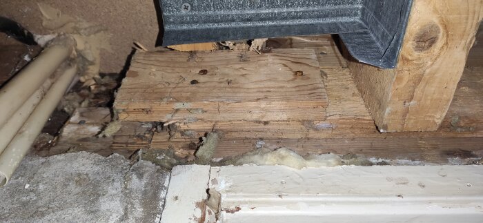 Skadade träsyllar i källare med tecken på fukt och röta, som behöver åtgärdas.