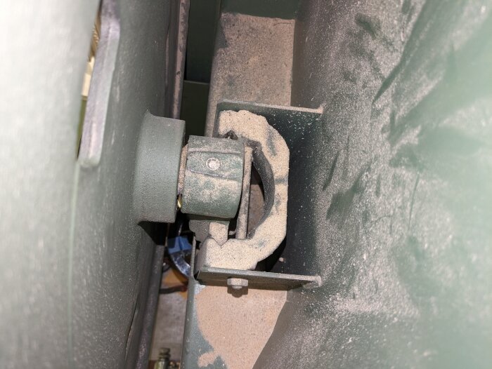 Bild på övre upphängning av maskin med synlig sättskruv nr 8 täckt av sågspån.