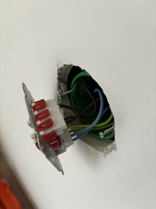 Öppen eldosa med brytare och synliga kablar i vägg inför installation av DIM-01.