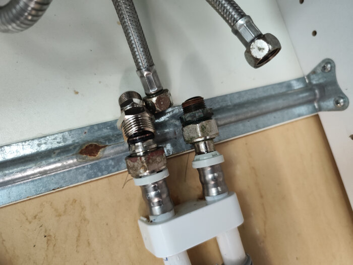 Vattenledningar och klämringar under installation av ny blandare.