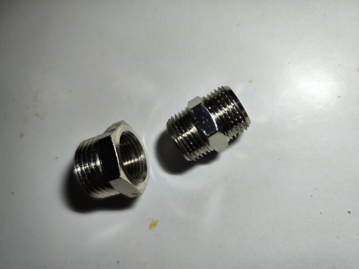 Två metalliska klämringar med gängade anslutningar på vit bakgrund.