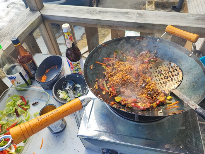 Matlagning av wok med grönsaker och chili i en utomhusmiljö med snö i bakgrunden.