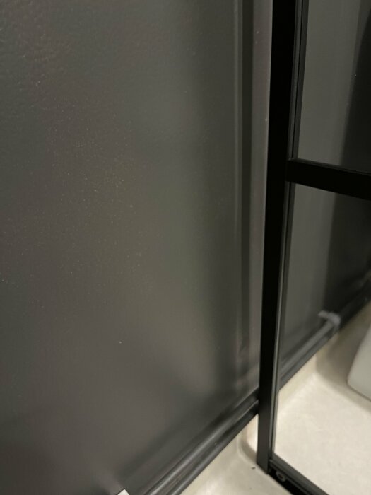 Närbild på en svart duschhörna med skjutdörrar monterad vid en vägg.