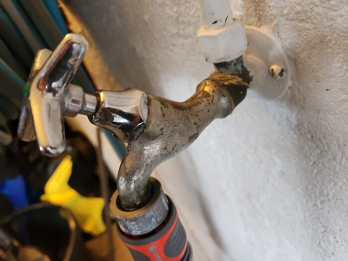 Vattenutkastare med inkommande anslutning och synliga gängor monterad på en vägg, lätt fuktig och möjlig läcka.