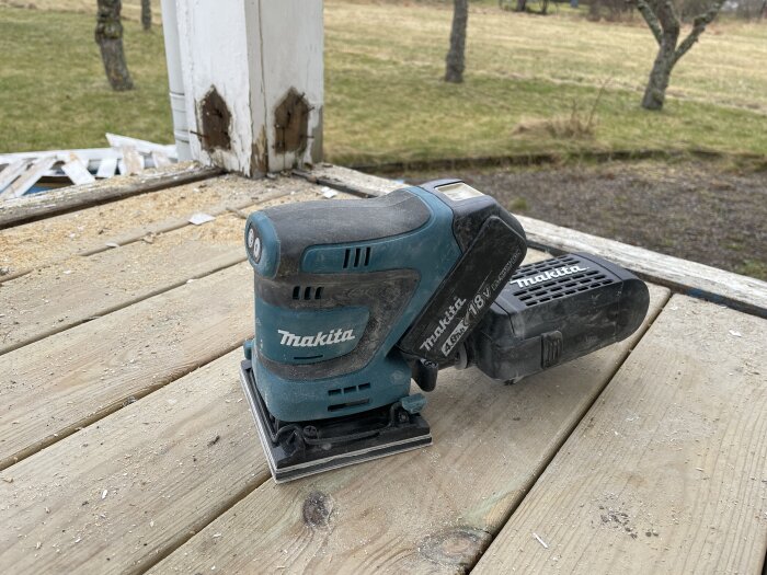 Batteridriven Makita planslipmaskin på träplankor utomhus.