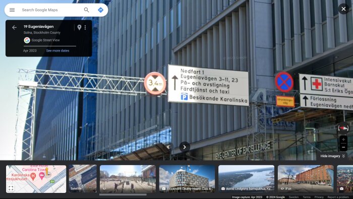 Skyltar med vägbeskrivning och höjdbegränsning utanför modern byggnad.