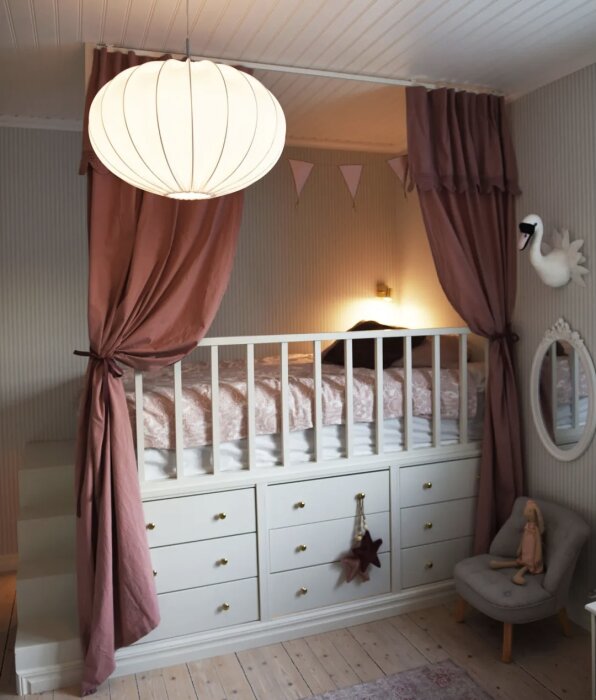 Elevated child's bed with white railing built over white drawers, with a decorative swan, in a cozy room.