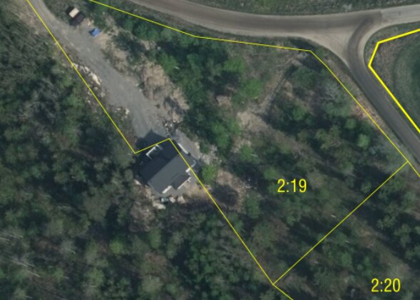 Satellitbild över byggplats med nybyggt hus och markerade gränser vid skogskant nära väg.