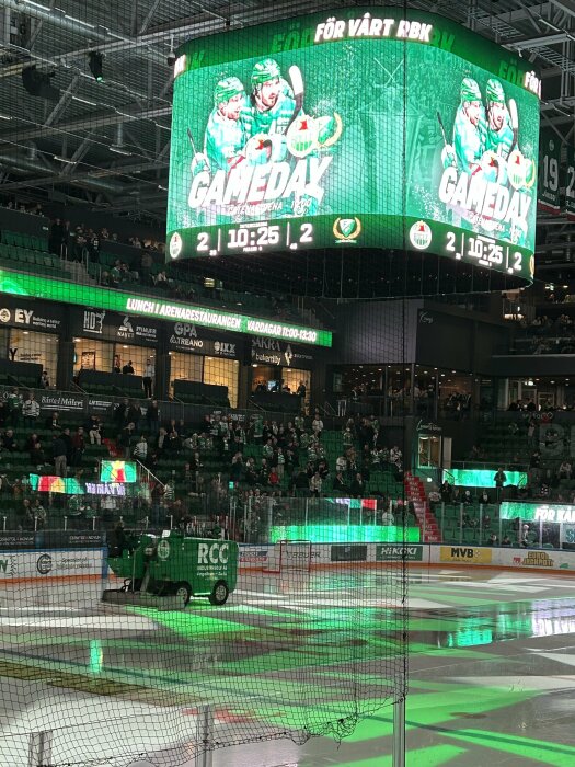 Ishockeyarena med stor skärm som visar "GAMEDAY" och ismaskin som jämnar till isytan.