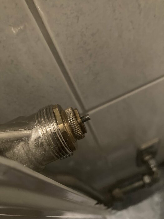 Närbild av en ej monterad duschblandarfäste mot en kakelvägg, fråga om rätt installation.