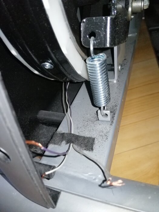 Närbild av en motionscykels interna komponenter med synliga avskurna trådar och transformator.