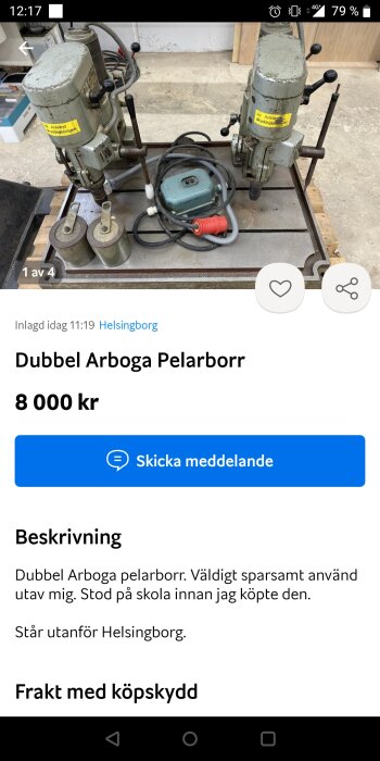 En dubbel pelarborr av märket Arboga, placerad på en verkstadsarbetsbänk, tillsammans med slangar och elkabel.