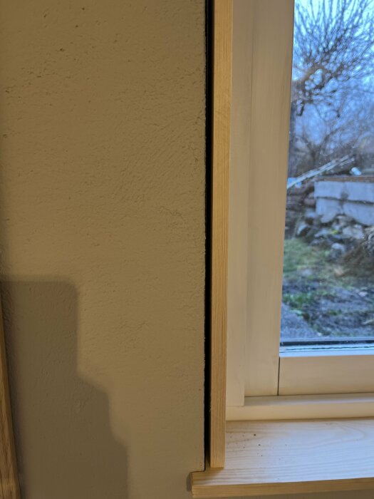 Närbild av ett ej färdigställt fönstersal vid en putsad vägg i källarplan.