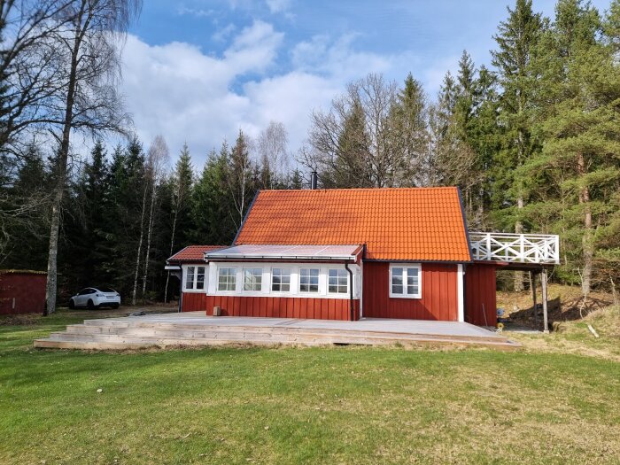 Rödmålad stuga med Falu rödfärg belägen i skogsglänta, välbelyst av solsken, utan synligt mögel på fasaden.