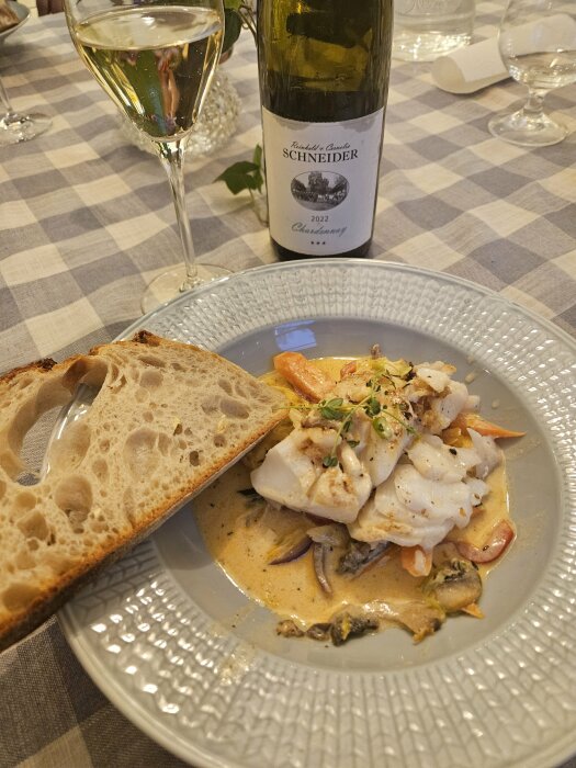 Fiskgryta med torskrygg och grönsaker serverad med ciabatta och ett glas Chardonnay.