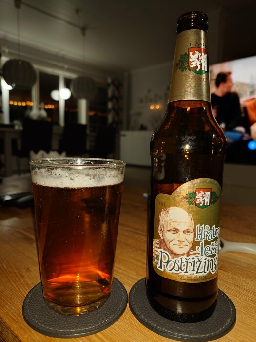 Flaska och glas med tjeckisk öl på bord framför TV.