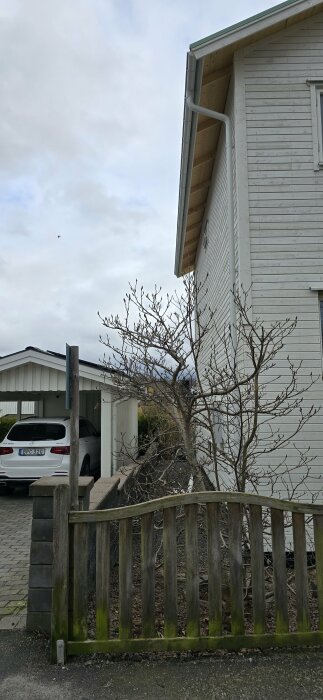 Utsikt av ett höjt hus med slät plåttak nära en carport med solpaneler och risk för snöras.