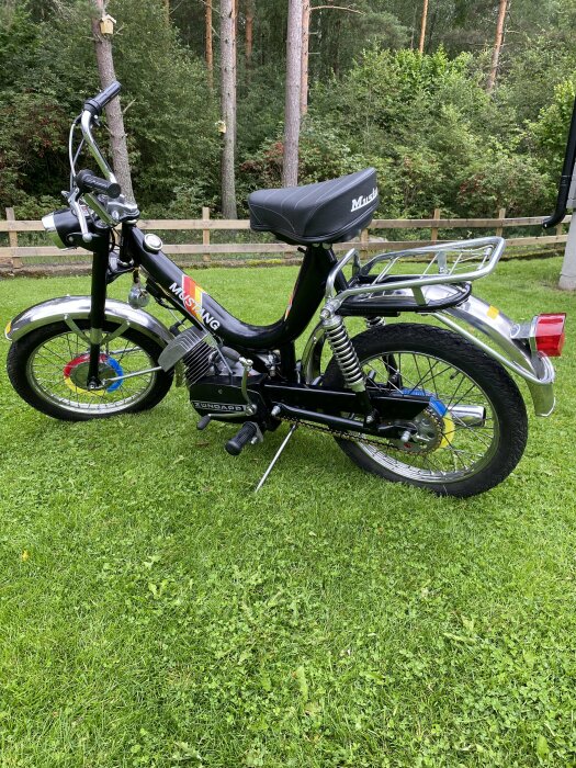 Svart Zundapp Mustang moped parkerad på gräs med tydliga varumärkesdekaler och ett högt styre.