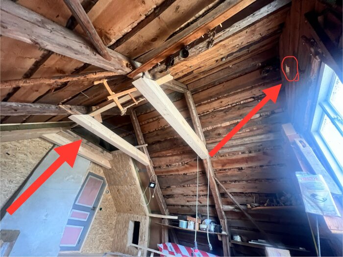 Renovering av äldre hus med öppet takstomme och pågående arbeten, pil pekar på ventilation vid yttervägg och murstock.