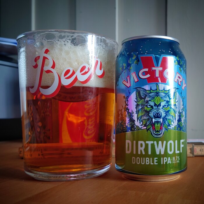 Ett ölglas fyllt med gulbrun vätska bredvid en "Victory Dirtwolf Double IPA" burk.