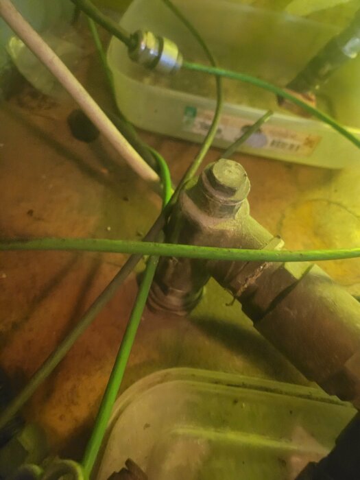 Närbild av rörkopplingar och ledningar med suddig bakgrund i gult och grönt.
