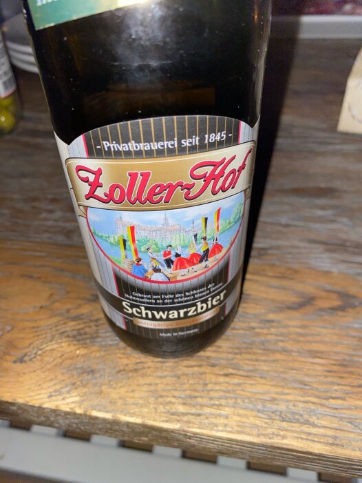 Flaska av Zoller Hof Schwarzbier på ett träbord, närbild på etiketten.