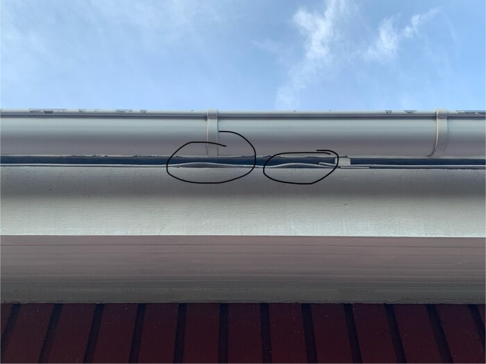 Takfot med potentiell ingång för getingar markerad med en cirkel, synlig glipa mellan tak och fasadbeklädnad.