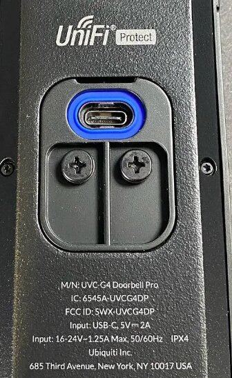 Närbild av en Unifi Protect dörrklocka med specifikationsetikett och synliga USB-C och AC-ingångar.
